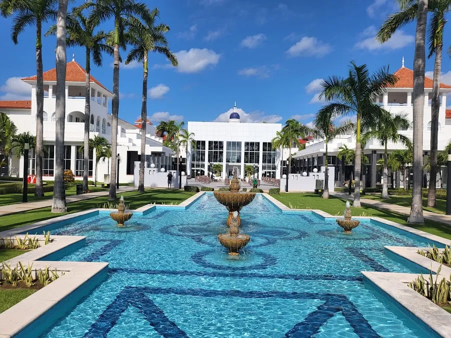 Alberca y fachada de estilo colonial del Hotel Riu Yucatán rodeada de palmeras